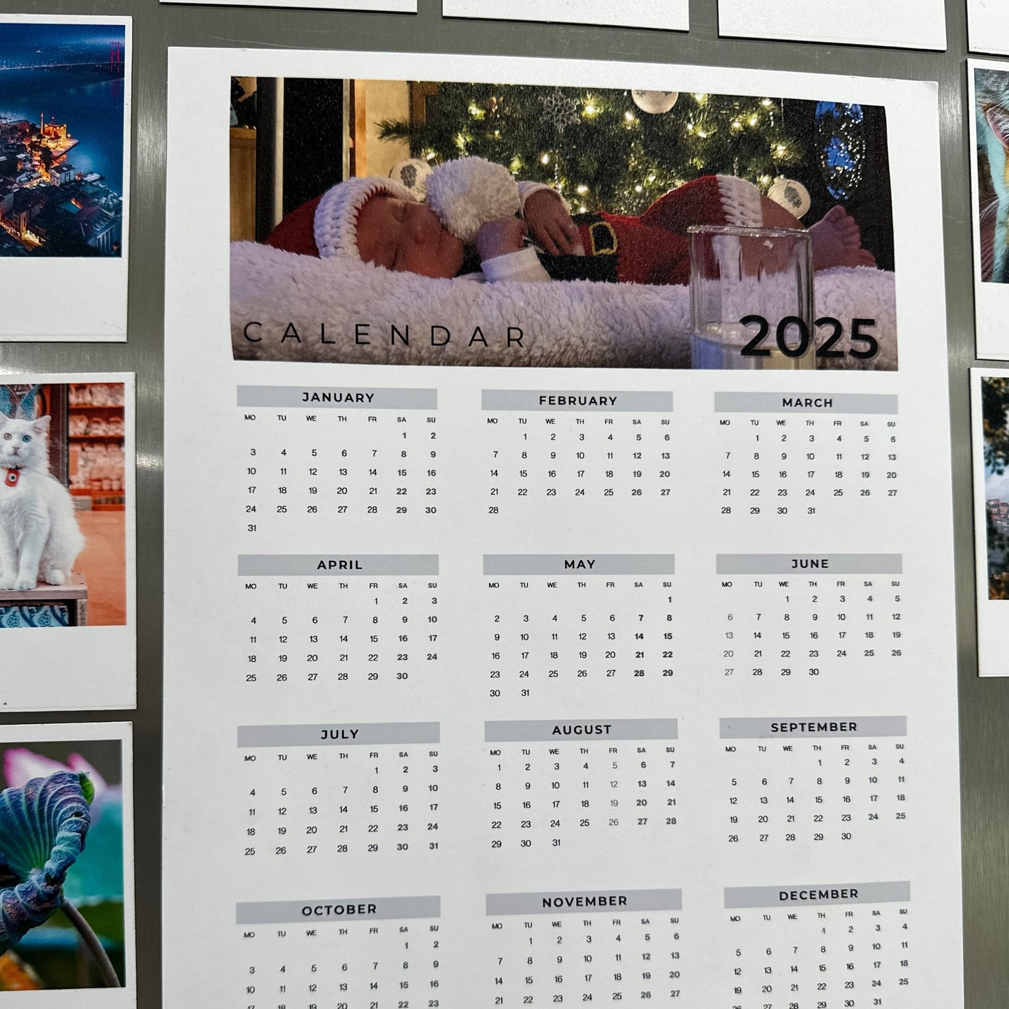 2025 calendar with a photo of a baby and a glass of milk on a stainless steel refrigerator.