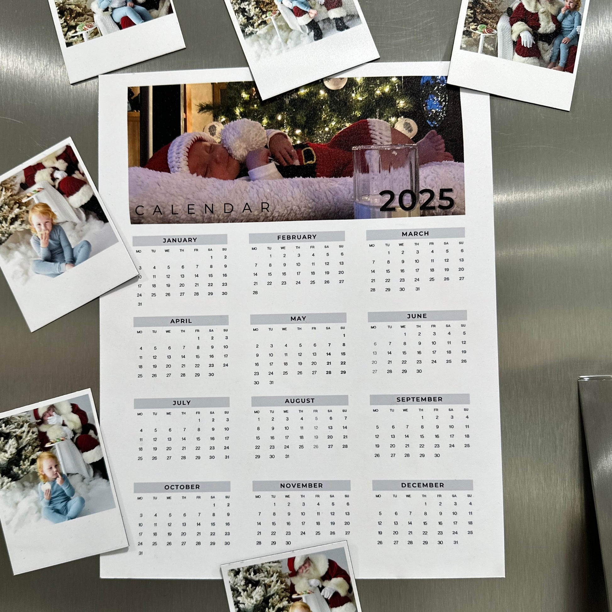 Calendar for 2025 with photos attached to a stainless steel refrigerator.