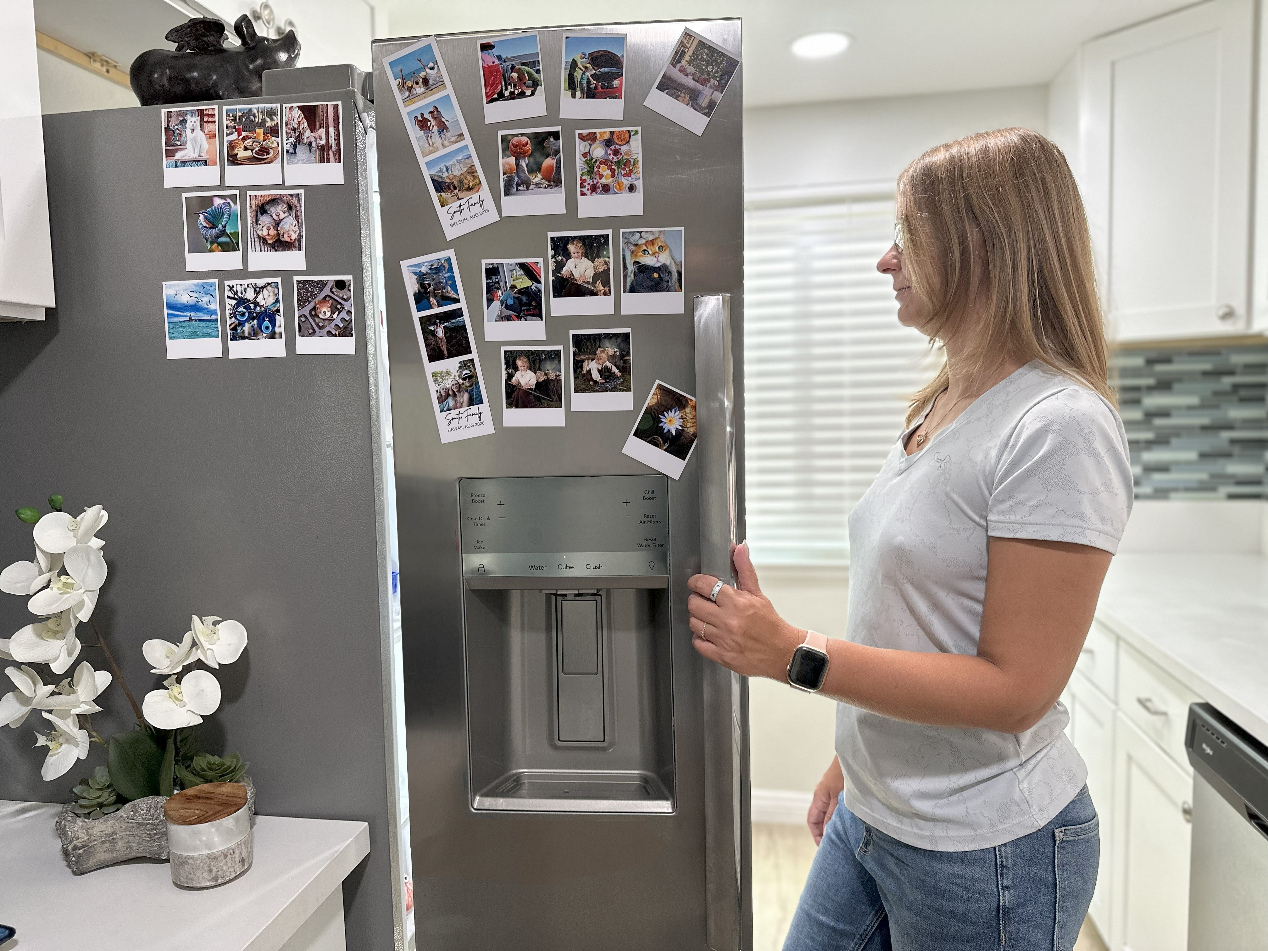 Woman standing in front of a refrigerator with magnets on it in a kitchen.