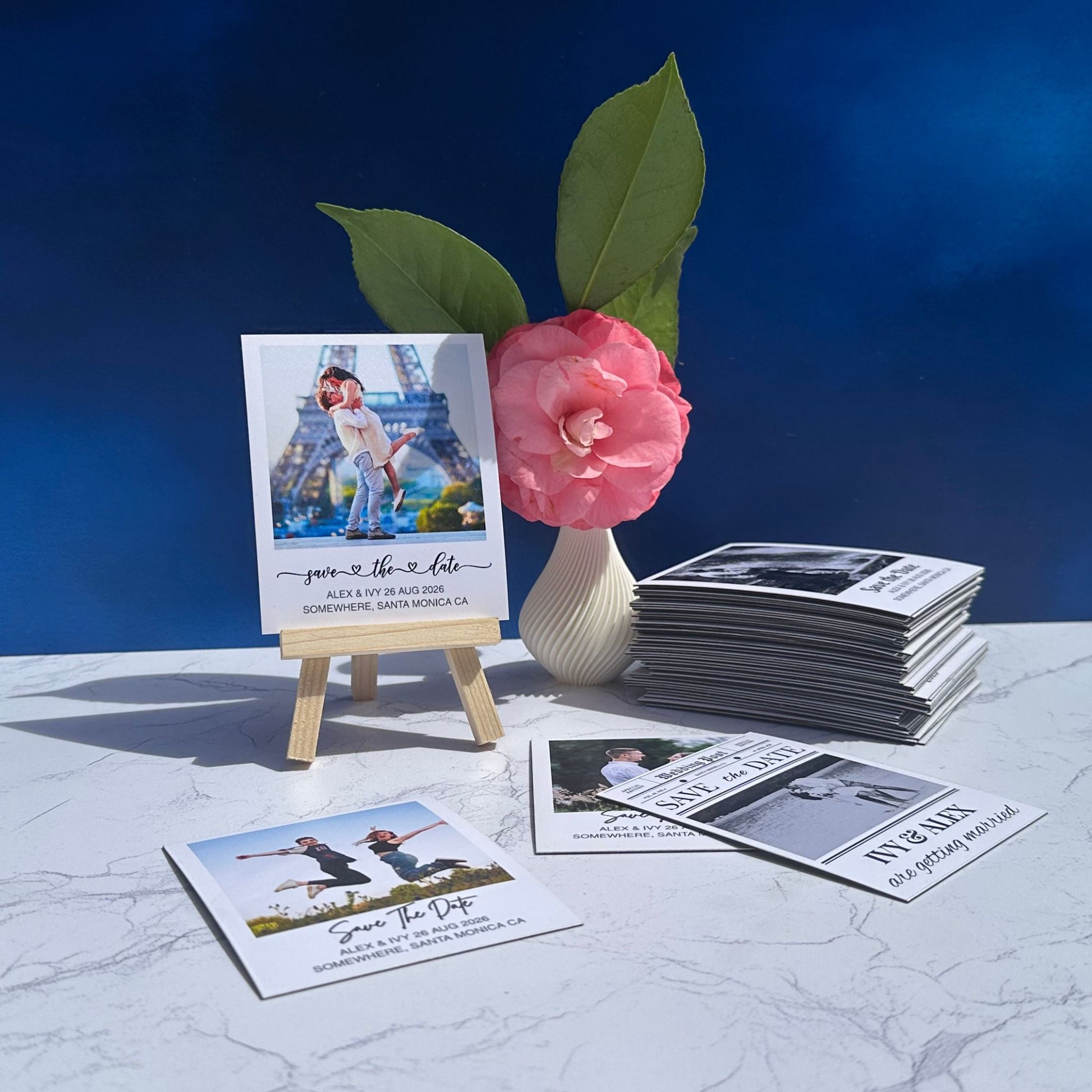 Set of save the date magnets with a pink flower and Eiffel Tower image on a blue background