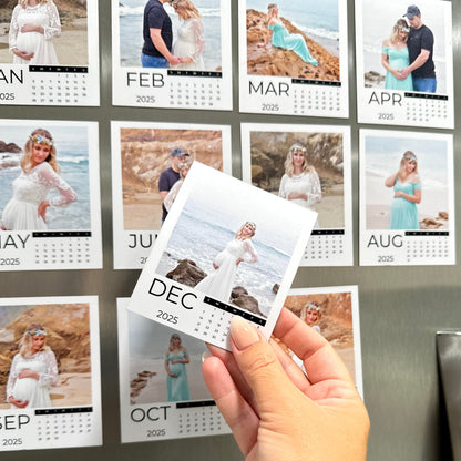 Calendar with various photos of a couple and a pregnant woman, held by a hand in front of a stainless steel refrigerator.
