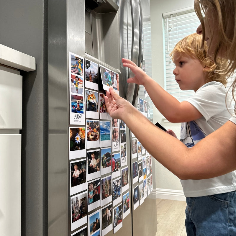 Child and adult looking at photo magnets on a refrigerator door
