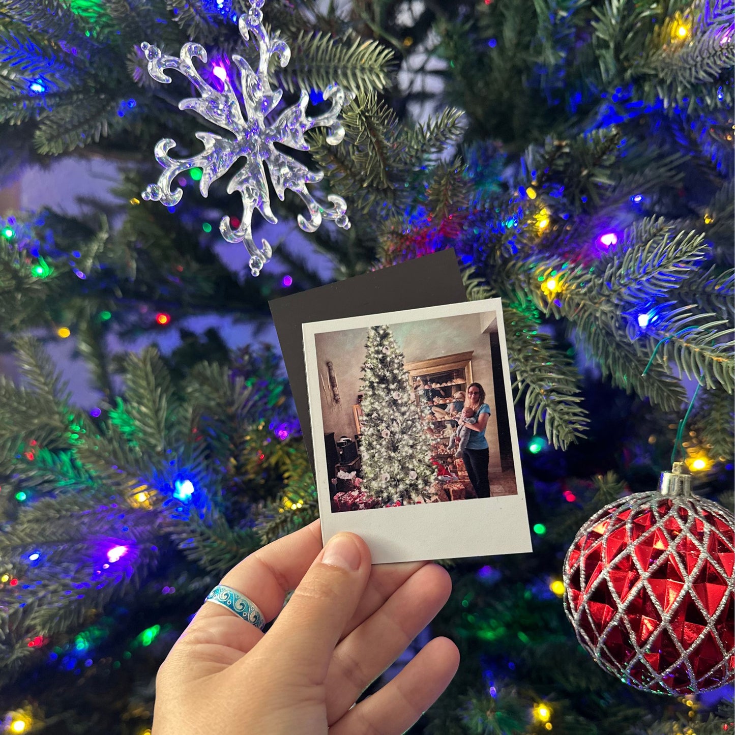 Polaroid-style Photo Magnet of a decorated Christmas tree held in front of a lit Christmas tree.