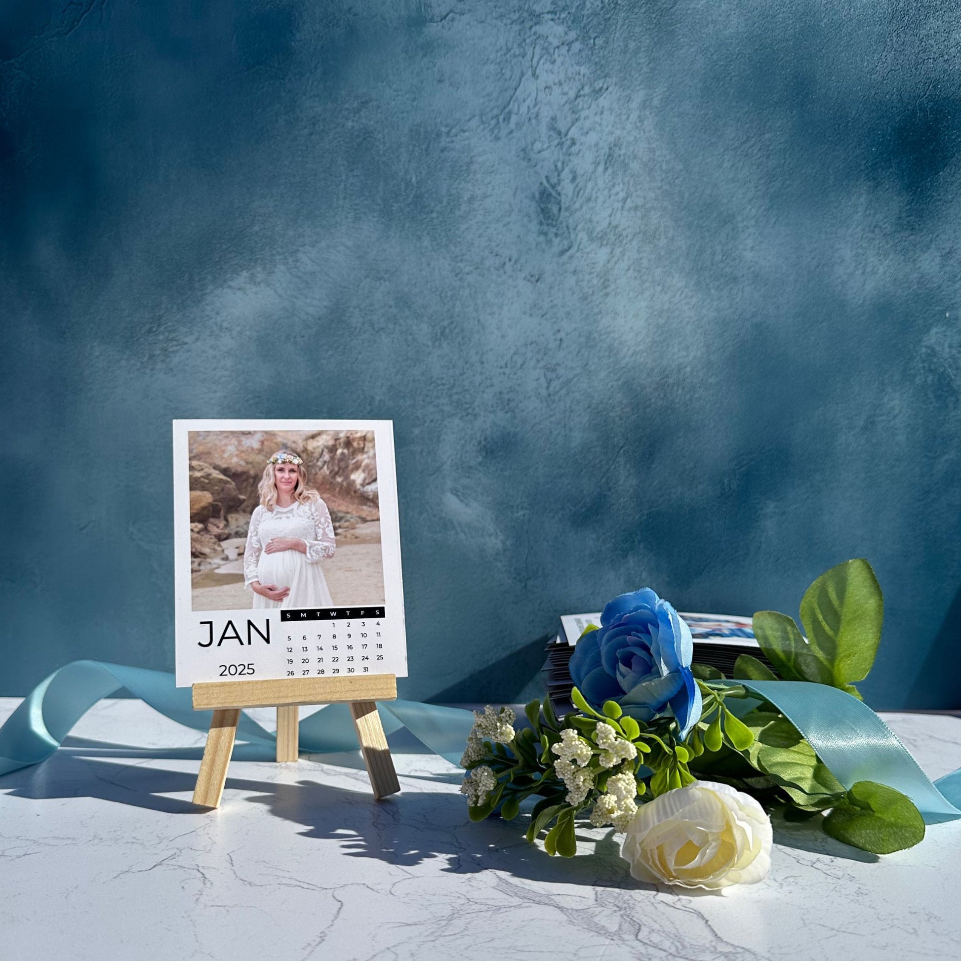 Calendar Photo Magnet with a photo of a pregnant woman on a stand, surrounded by flowers against a blue background