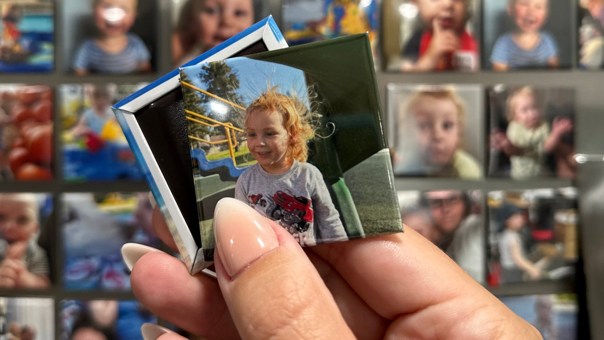 Person holding a 2x2 custom photo magnet with a child's picture on a grid of other photos.